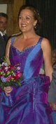 The central panel of the corset bodice is pleated to emphasise the variable blue/ pink light effects. The entire neckline and armhole area is beaded in a variety of toning crystals, pearls, and faceted glass stones, all in shades of blue, pink purple and lilac. Constantly, some part of the gown will attract the light - from the focus of beading at the waist and neckline to the clusters of crystals, pearls and sequins which support the swags of organza on the skirt.