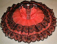 This dramatic 'Don Quixote'ballet tutu was commissioned by Cheshire Youth Ballet for a series of performances at the Lyceum Theatre, Crewe. The red silk bodice and matching net skirts were set off by the vibrantly contrasting black lace decoration. A matching headdress was constructed with a spanish comb effect
and red silk roses.